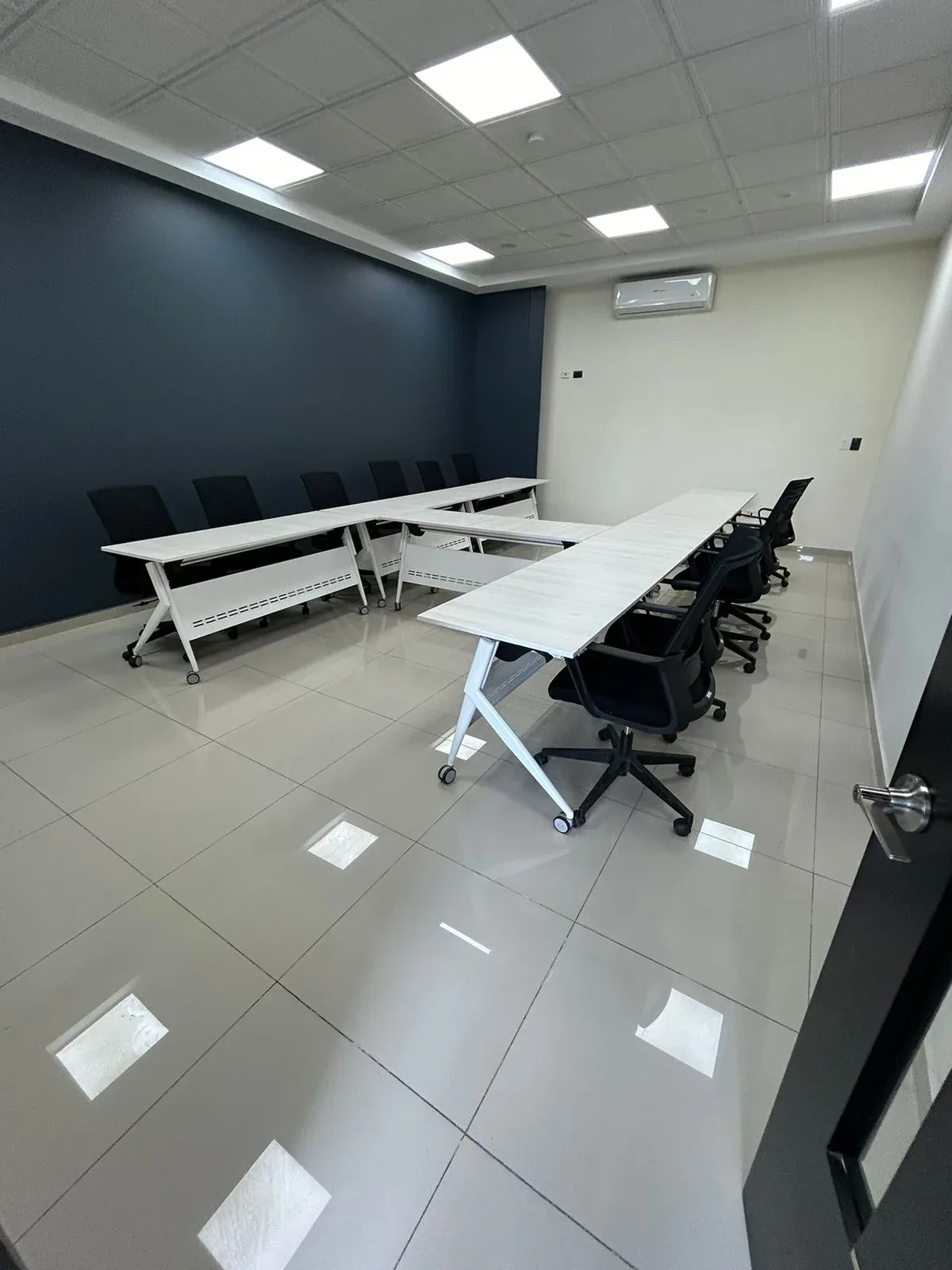 Sala de capacitación vista desde la puerta, con las mesas montadas en U
