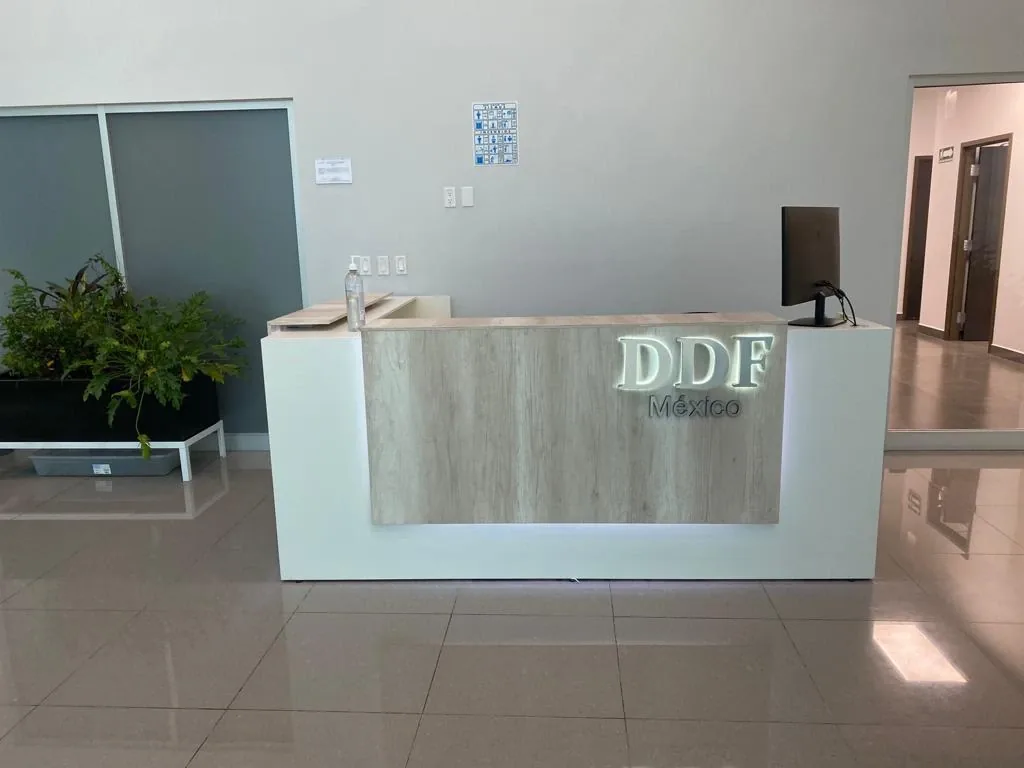 Mostrador de recepción con frente de melamina clara y logotipo iluminado de DDF México