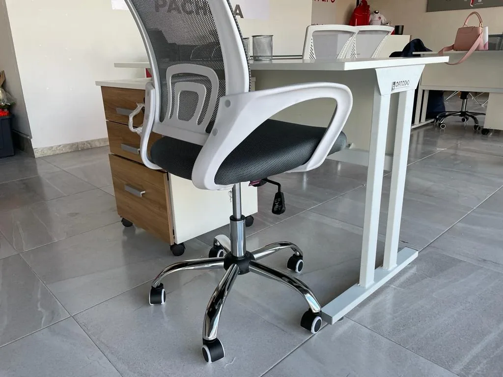 Silla operativa de malla y cajonera rodante junto a escritorio con pata metálica